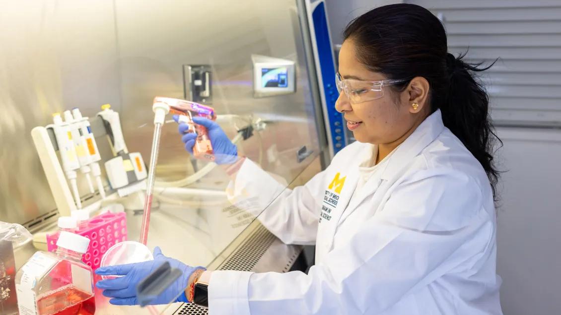 A researcher wearing safety goggles works with a pipette in a laboratory.