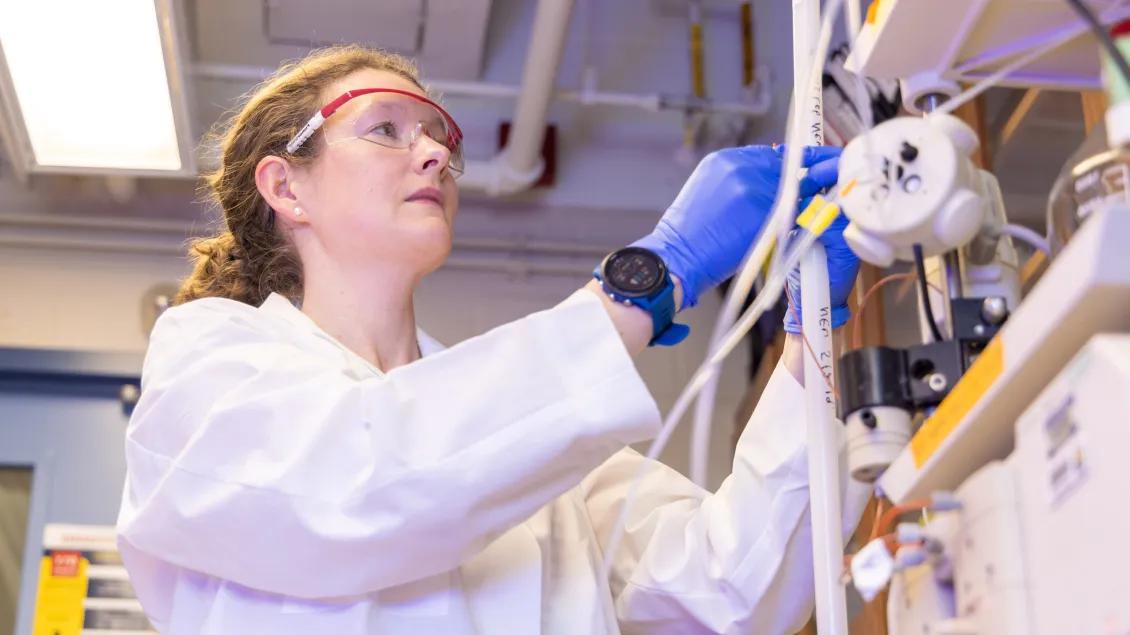 A researcher adjusting tubing on laboratory equipment