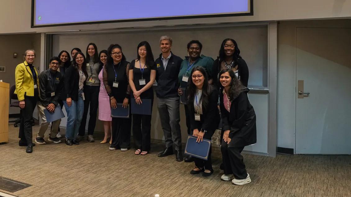A group of people pose for a photo at the front of a lecture hall