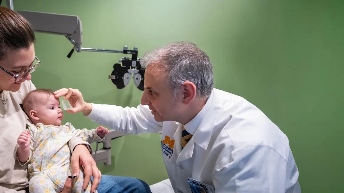 Dr. Christopher Gappy examining a baby being held by its mother.
