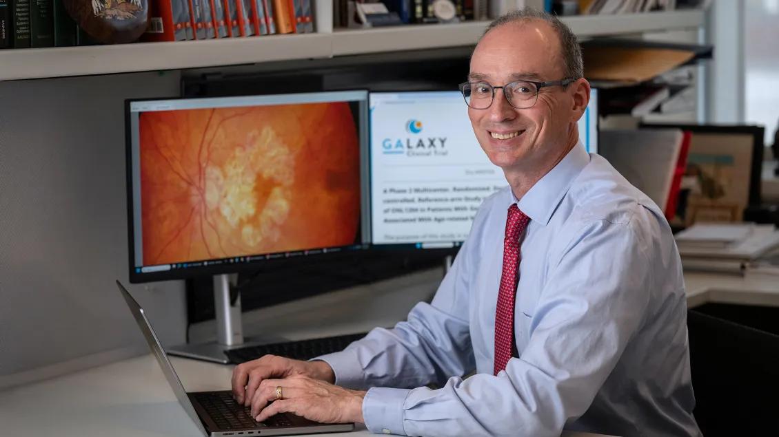 Dr. David Zacks in front of two screens, one with a retina and the second with the Galaxy