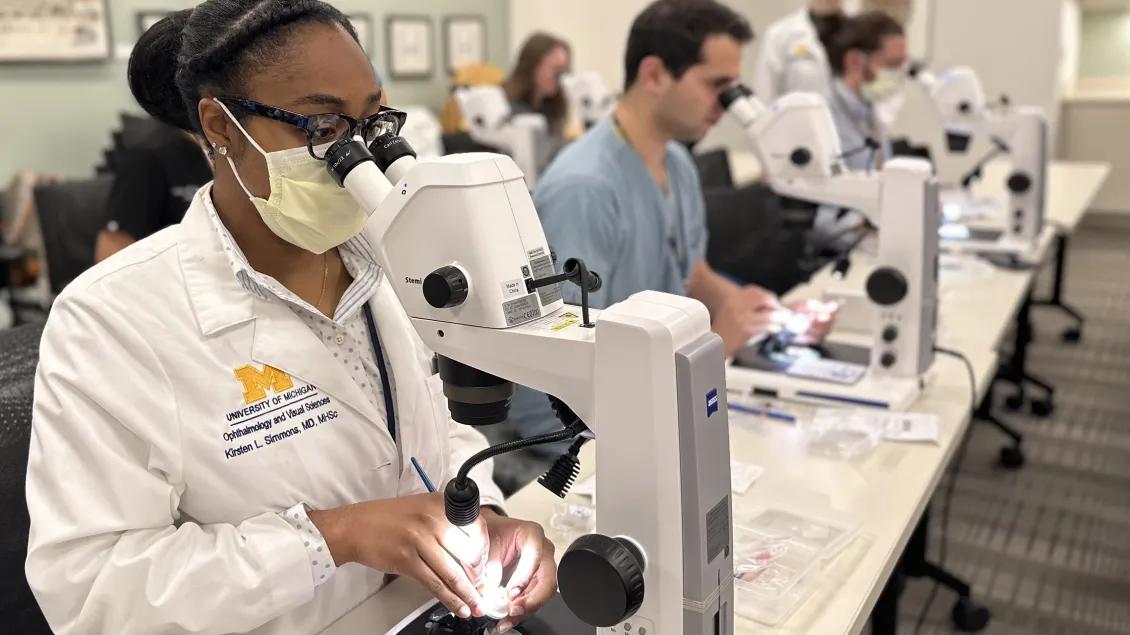 Four residents in surgical training sitting before microscopes 