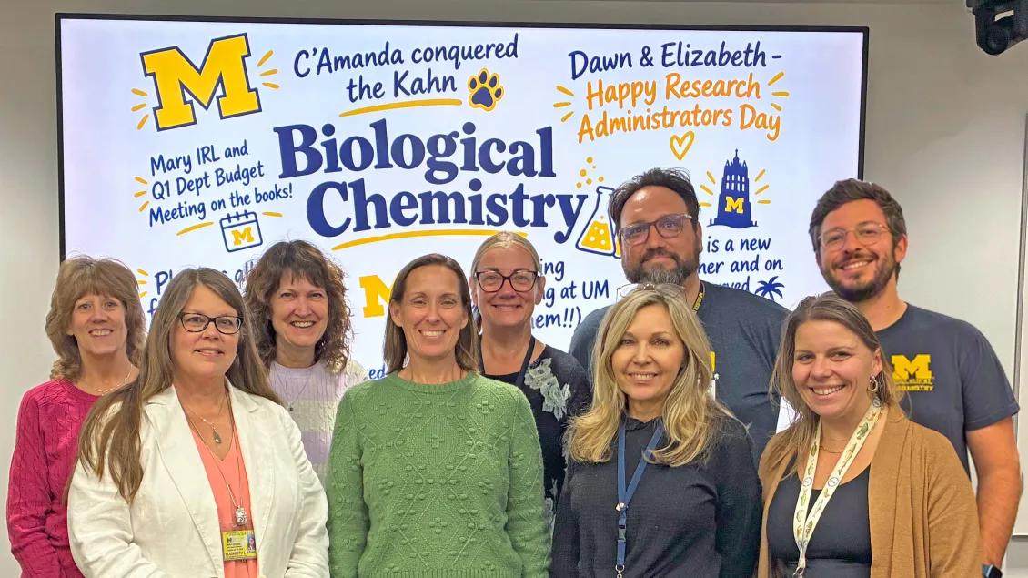 group photo of administrators in front of screen with accolades
