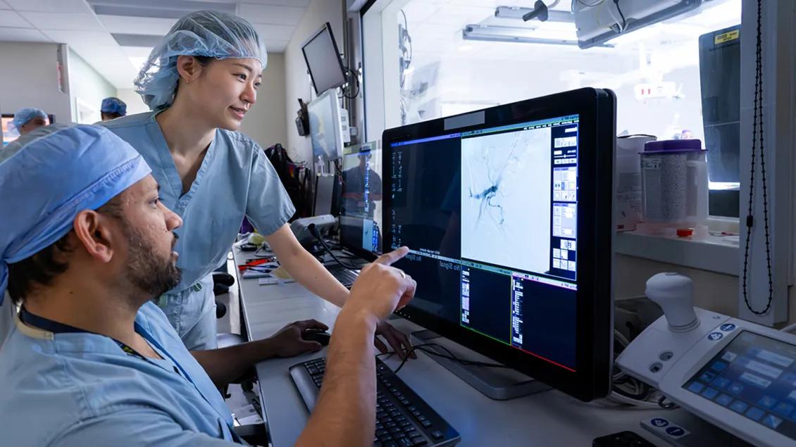 Interventional Radiology faculty and trainee looking at images on a computer.