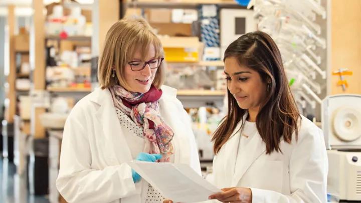 faculty and student discussing documents in a lab setting