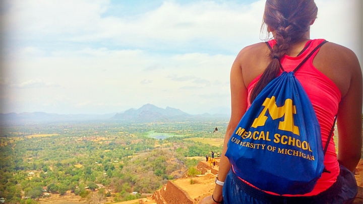 Back of young female with brown braid and blue U-M Medical School backpack overlooking scenic moutain area