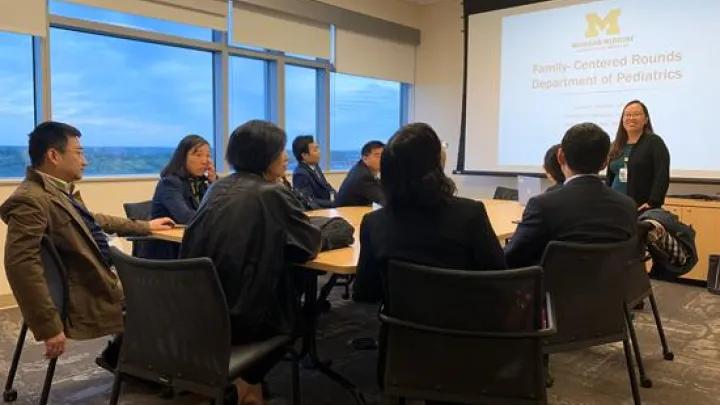 A group of people around a table in a working session with a presenter
