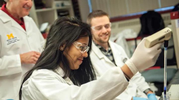 Three people in lab coats working together in a lab