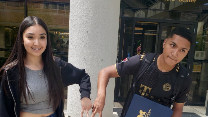 two students stand side by side in front of an architectural structure, exuding a sense of camaraderie and joy