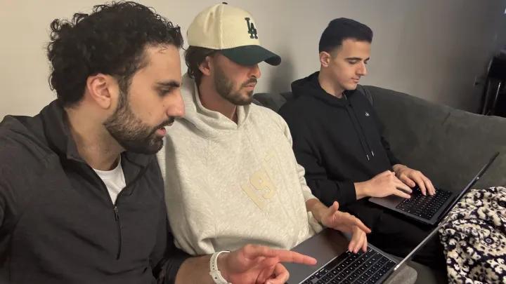 Three medical students sit on a couch working on laptops