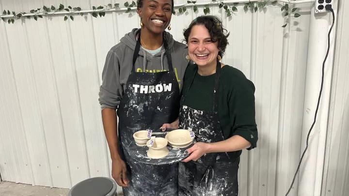 Two women holding freshly thrown pottery
