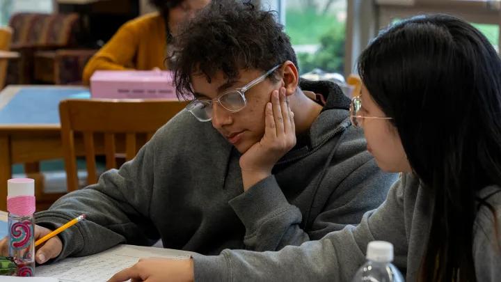 Undergraduate student coaching a middle school student in math