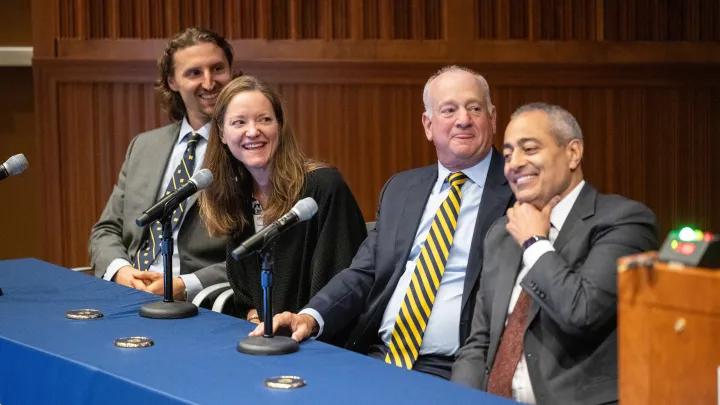 Four Alumni Day panel participants in sitting at a table covered with a blue tablecloth