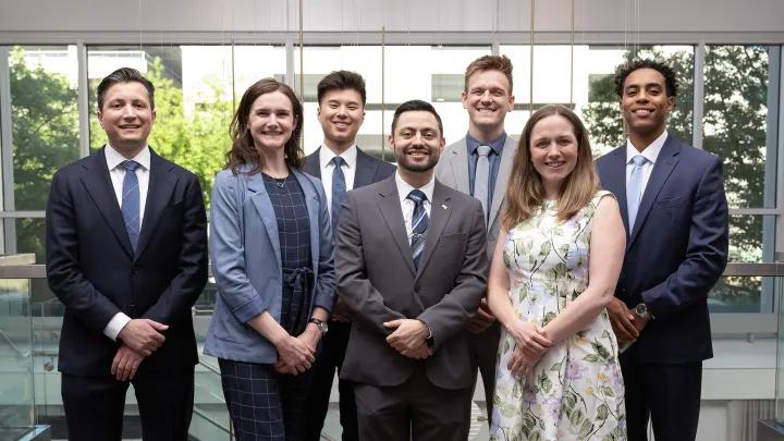Ophthalmology residency class of 7 standing in front of a bank of windows.