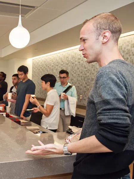 Students in cafeteria with young man in foreground gesturing