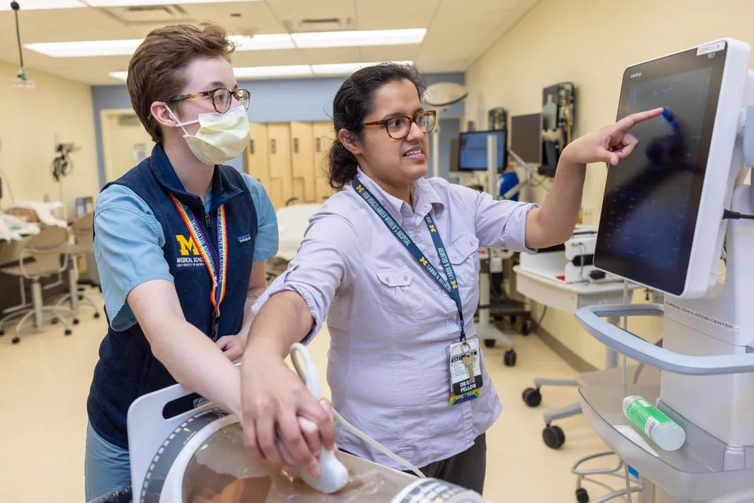  obgyn fellow teaches studuent during lab simulation while showing scans on a monitor 