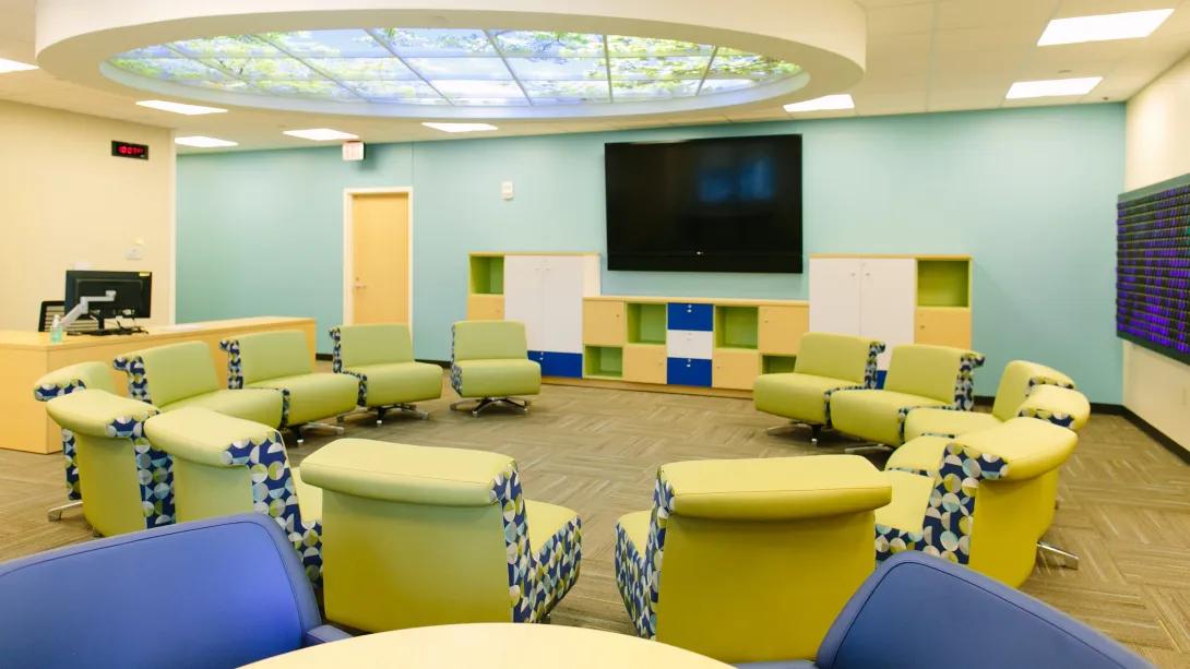 empty room with fake sky ceiling lights and brightly colored cushioned seats organized in a circle