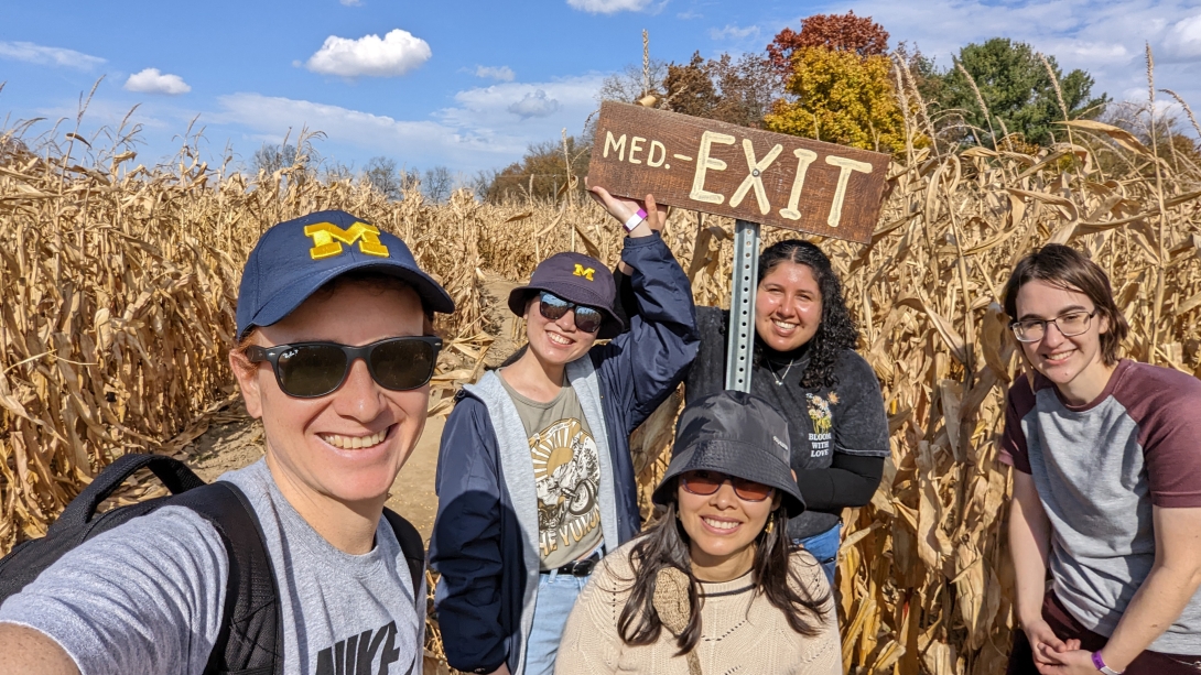 five college biological chemistry students in a corn maze taking a picture next the exit sign
