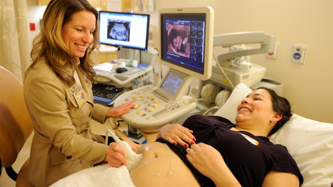 ultrasound tech scans belly of woman 