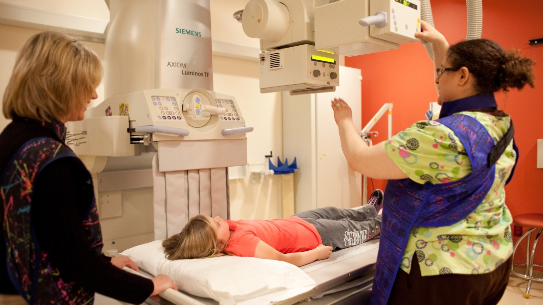 X ray technician moves scanner over child 