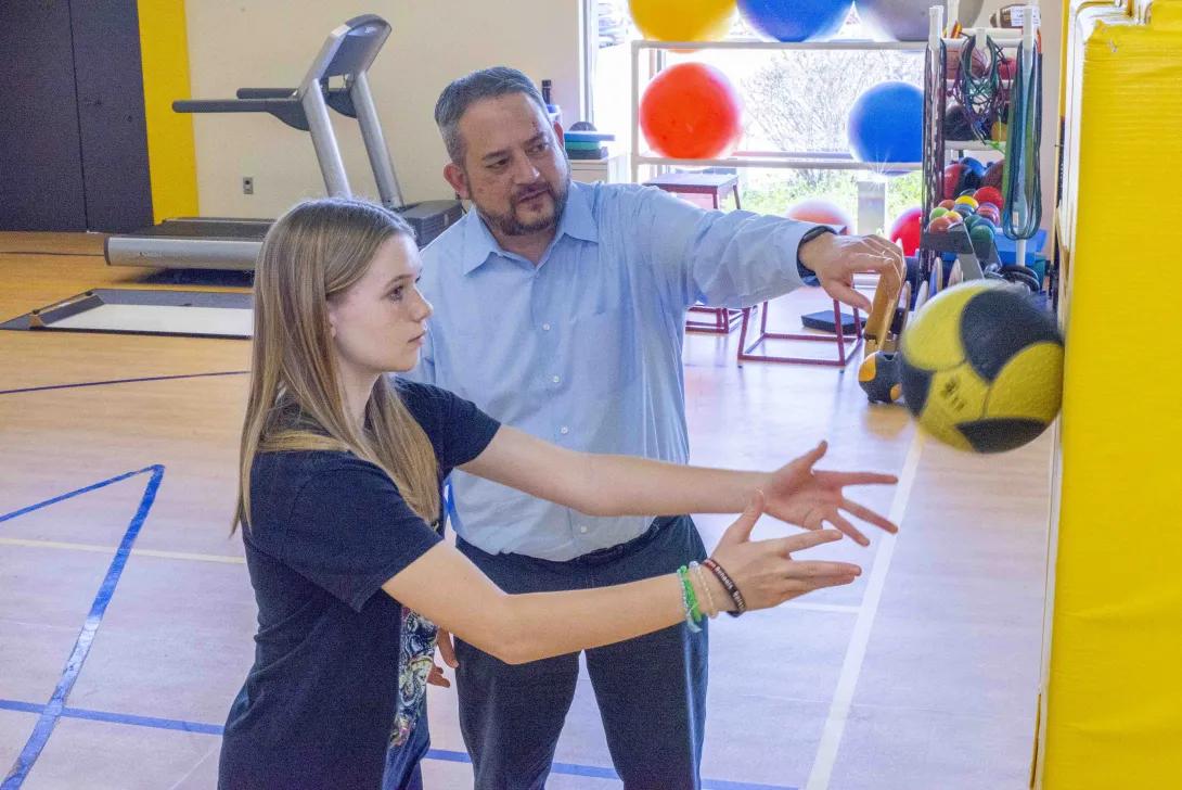 doctor performing exercises with medicine ball on wall