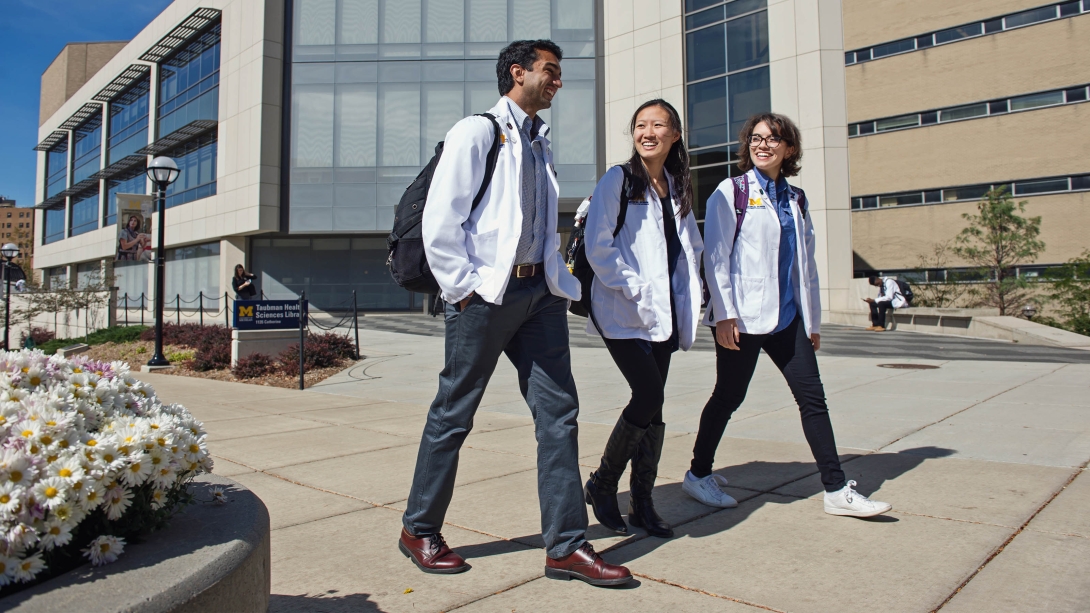 Medical students walking and talking by hospital in white coats