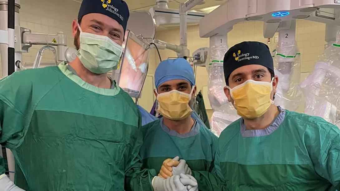 Doctors in green scrubs holding hands with masks on