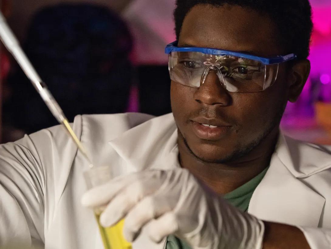 Person with goggles using a test tube