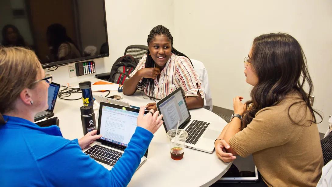 Three people sitting around a table talking