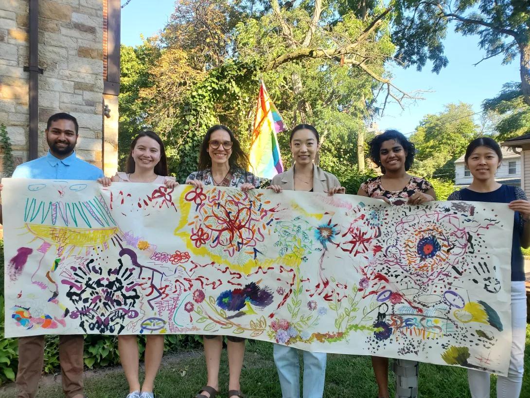 Students holding colorful painted banner smiling