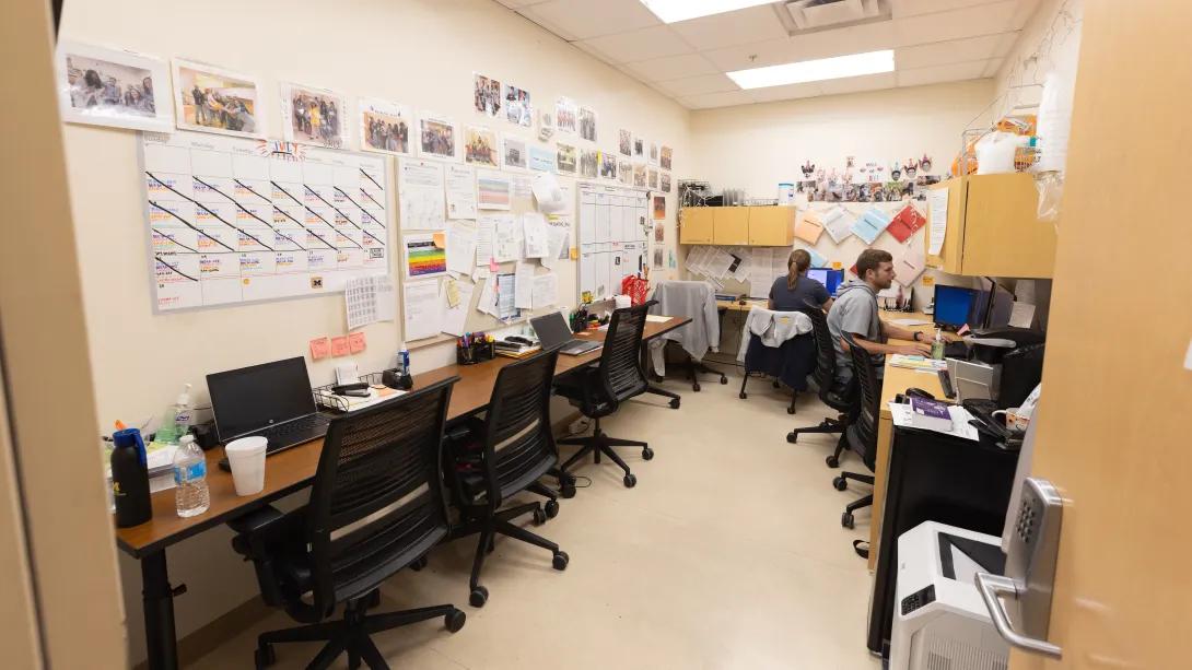 a room with several people sitting at desks and computers