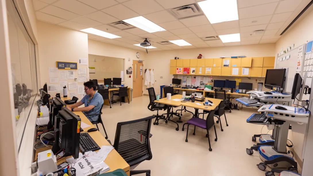 a room with persony computers and a person sitting at a desk
