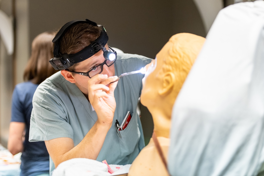 A student practices a nasal exam in the simulation lab