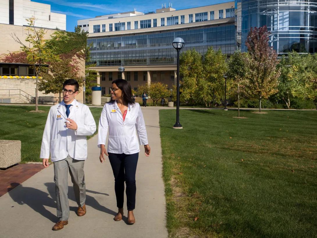 Two people walking outside on the Michigan medical campus