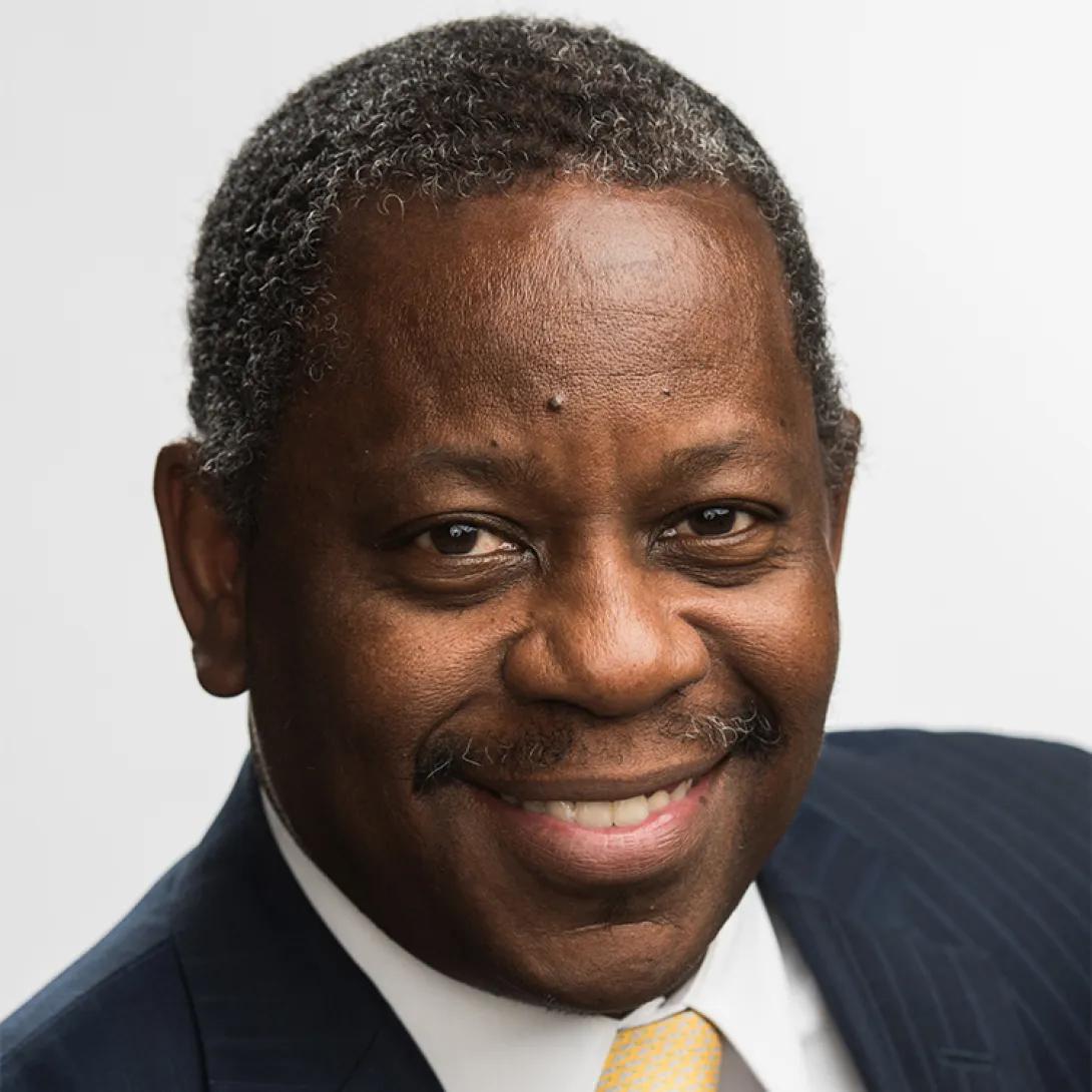 Headshot of Tony Denton wearing navy blue suit jacket and pale yellow tie