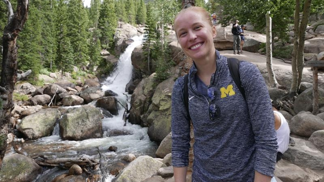 Woman smiling while standing next to a waterfall 