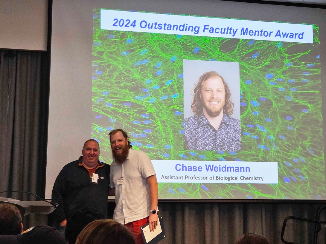 Chase Weidmann onstage, receiving a faculty mentor award