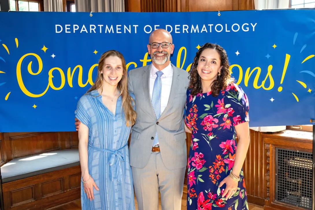 Three individuals standing in front of a "Congratulations" banner