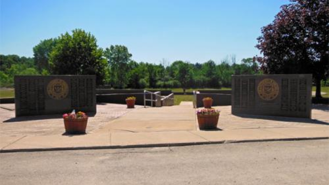 Two memorial walls with official seals and words, and some flower pots in front and behind them