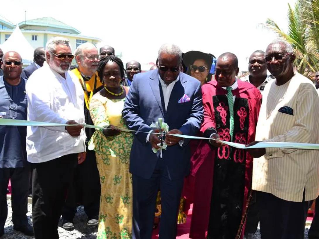 A group of people gathered around a man cutting a large ribbon