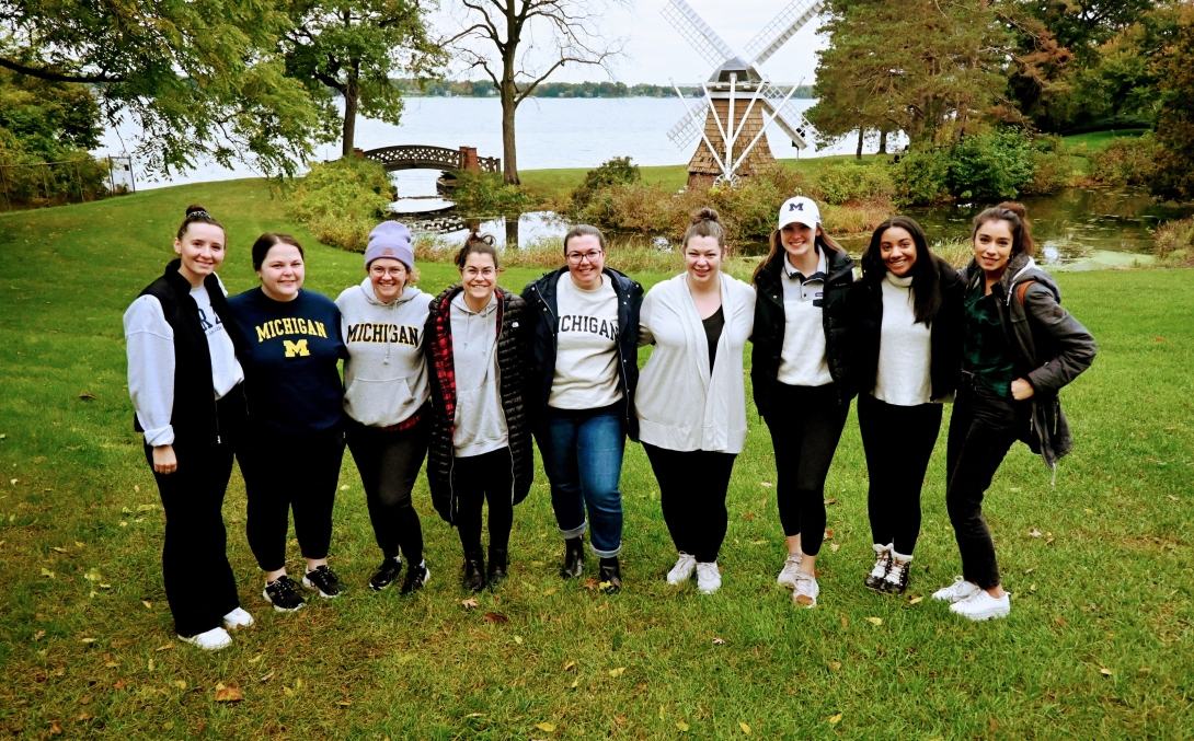 girls standing together while some wear UofM sweatshirts