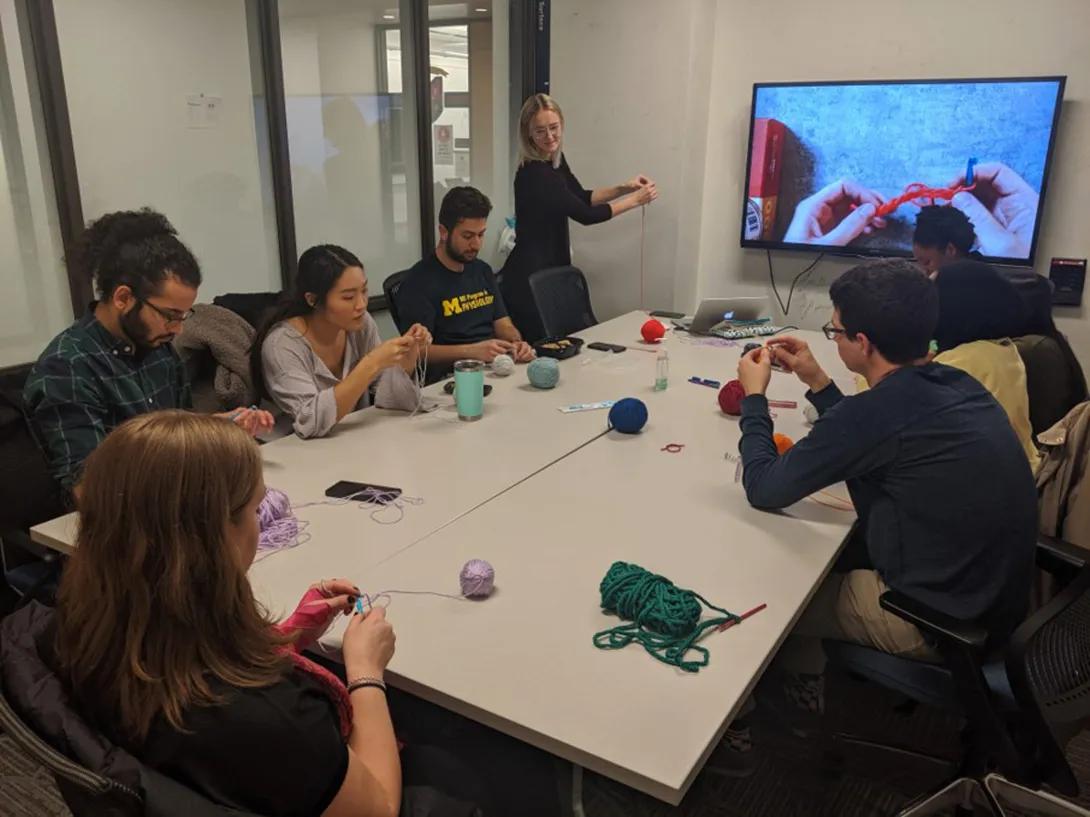 people crocheting around table