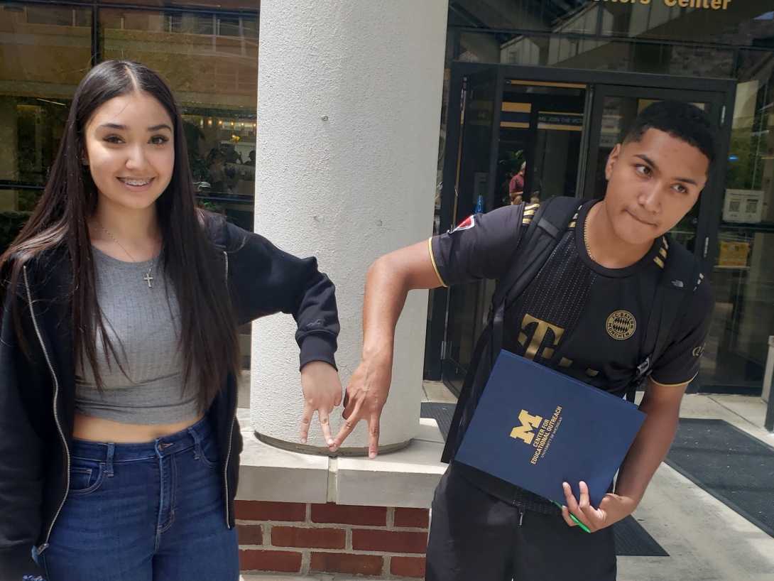 two students stand side by side in front of an architectural structure, exuding a sense of camaraderie and joy