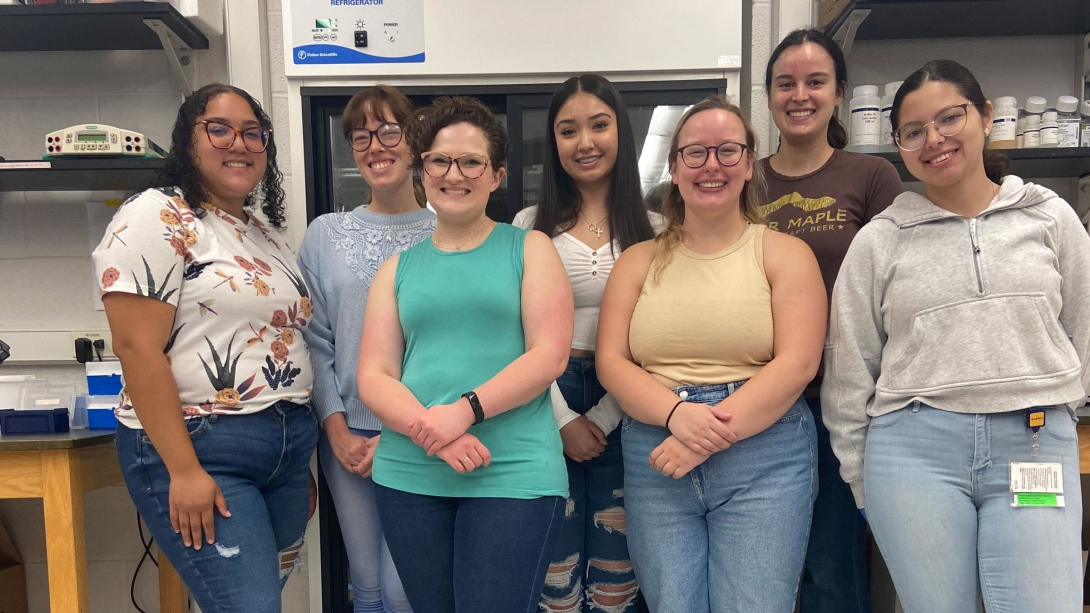 human genetics students smiling at the camera in a lab setting