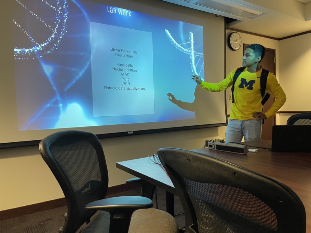 Human Genetics student presents lab work on a projector screen