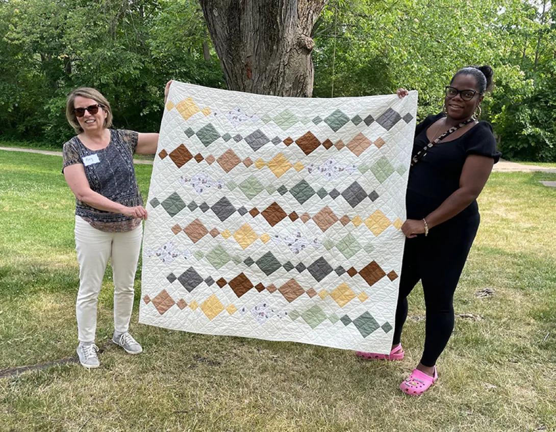 Mary Freer and Katie Ellis hold one of Freer's quilt