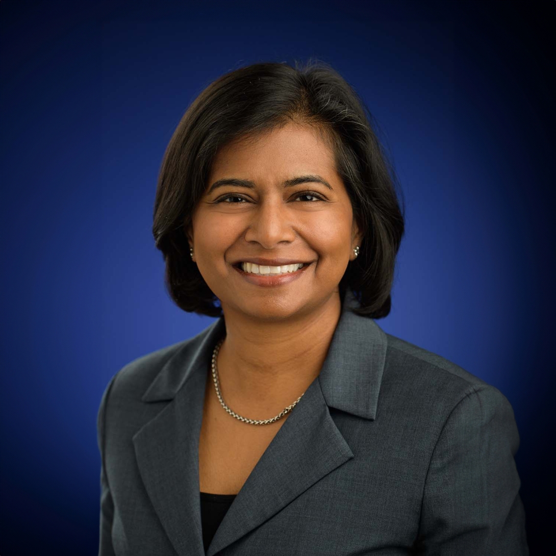 Smiling portrait of Santhi Ganesh, M.D. She has short dark hair and is wearing a gray blazer and a simple necklace.