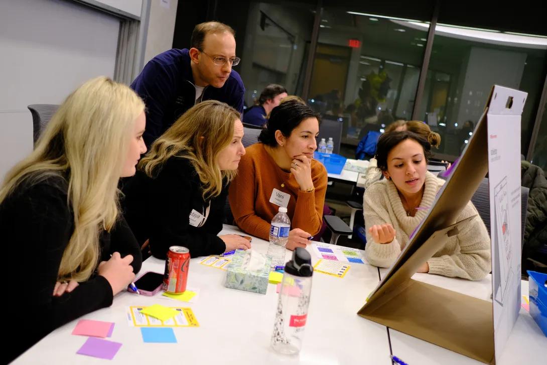 Group of people looking at post-it board.