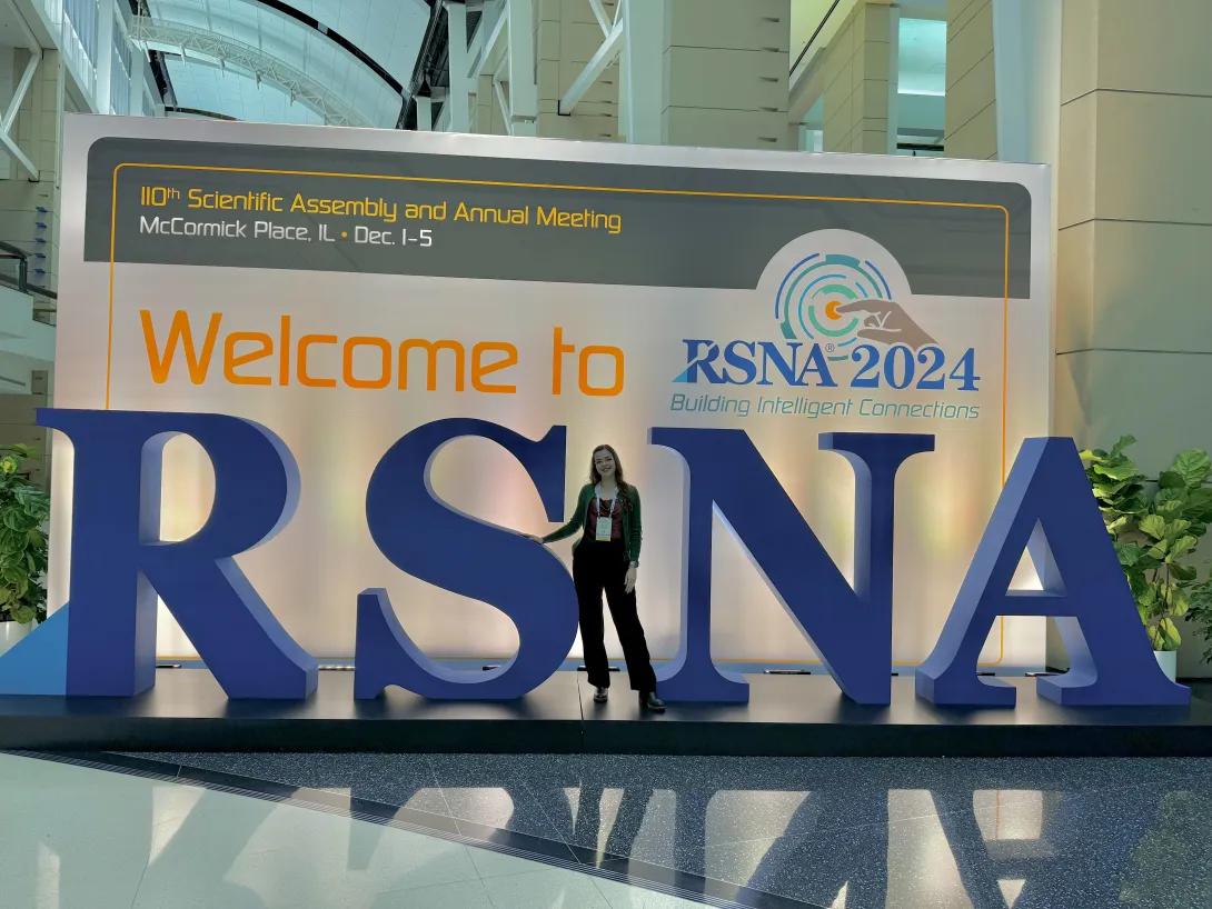 Meliz Ozkan stands in front of giant letters RSNA at a conference