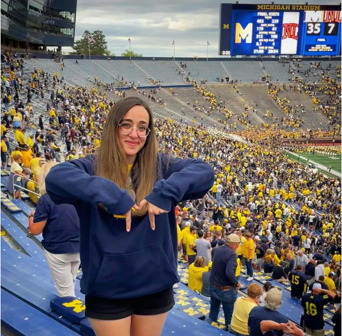 Joanne making the letter M with her fingers at the Michigan Stadium